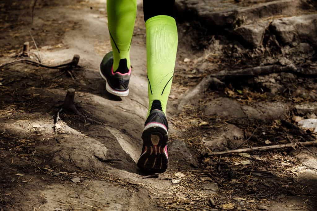 anti-blister socks:girl runs a marathon stone trail. closeup legs in compression socks and running shoes
