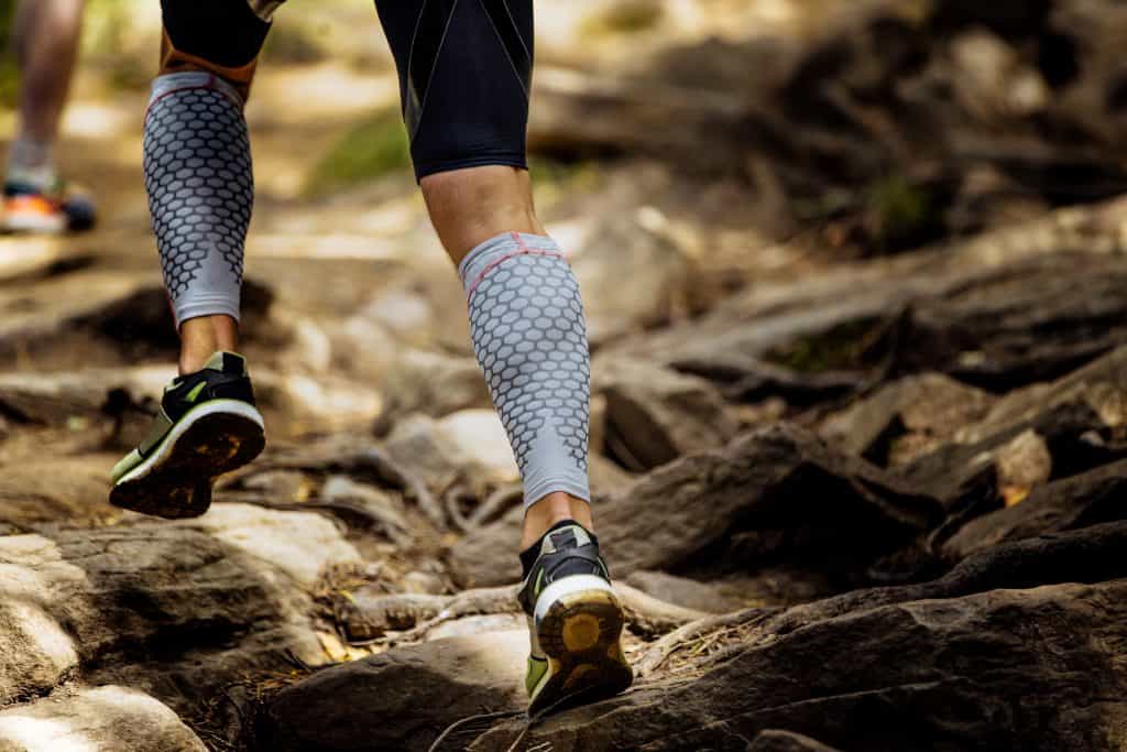 anti-blister socks:marathon runner running rocks in mountain. closeup of legs compression socks and shoes