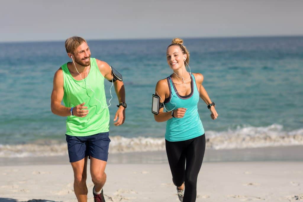 Young couple smiling while jogging at beach