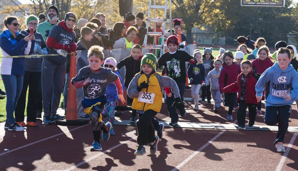 Kids running in a marathon with parent and people cheering on the side