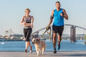 man and woman running with a dog