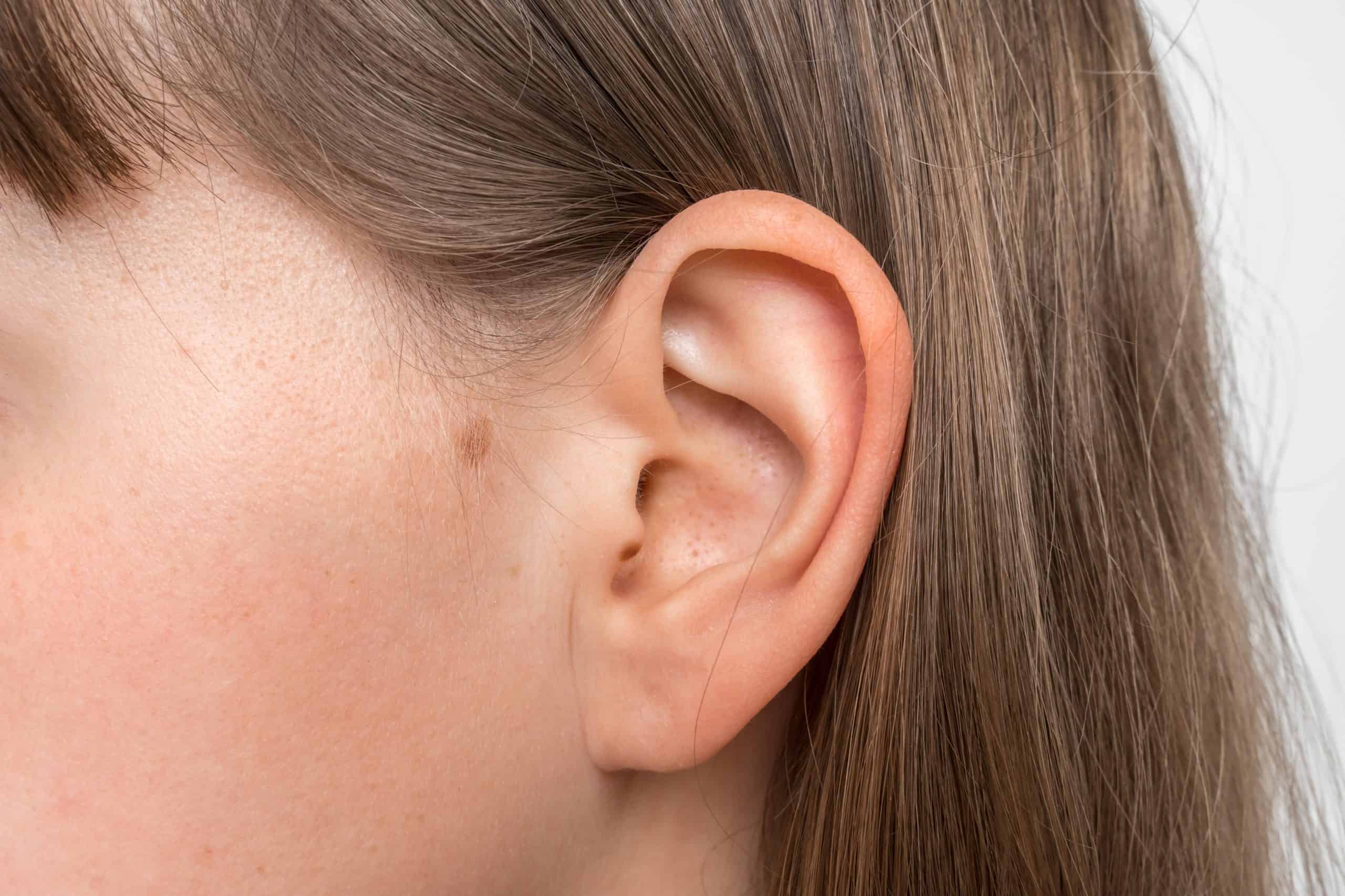 Close up of human head with female ear - listening or deafness concept