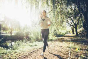 Morning Joggers: Fit woman jogging in park sorrounded by trees