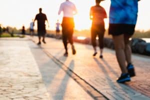 Blurred group of runner are running in park at evening sunset. People walking and exercise. Fitness and healthy activity lifestyle.