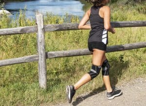 Female cross country runner racing with two knee braces