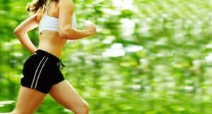 is a 6 minute mile good: young woman runner in a green forest.