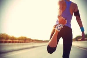 How to Start Running When Overweight: young fitness woman runner stretching legs before run
