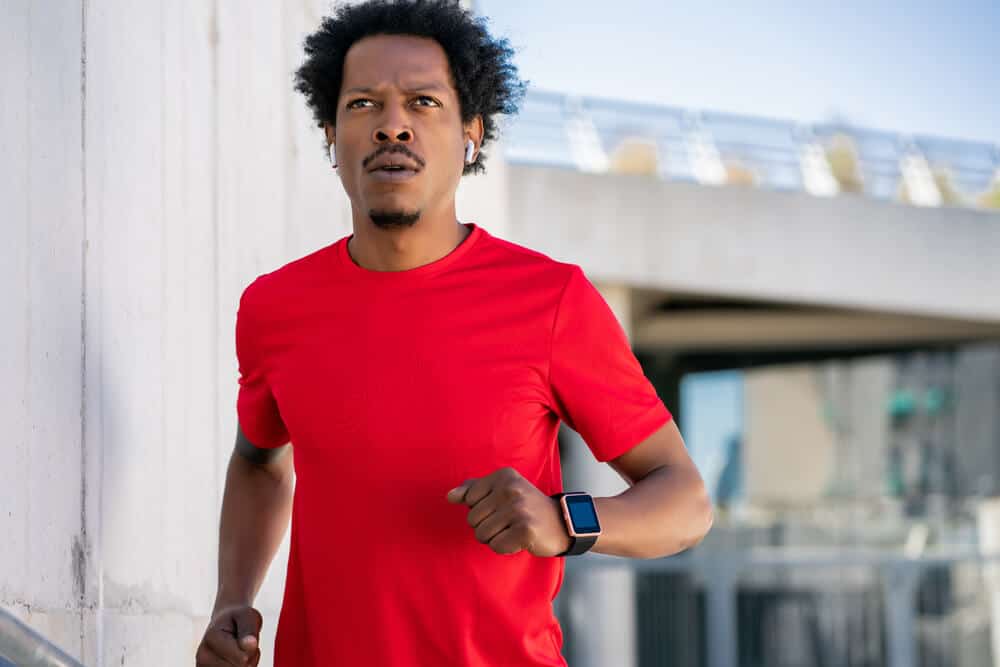 young man in red shirt listening to music while running