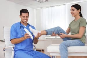running shoes with arch support: Orthopedist fitting insole on patient's foot in clinic