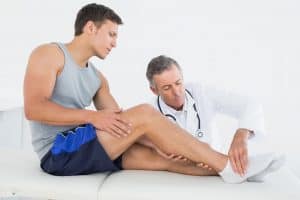 Side view of a young man getting his leg examined