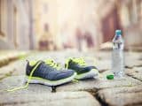 Shoes on cobblestone road next to water bottle
