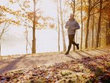 Fit male runner training in the park during cold sunny autumn morning