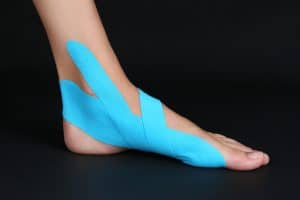 Female foot with physio tape on black background