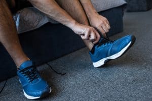 how to stretch sneakers for wide feet: man tying running shoes