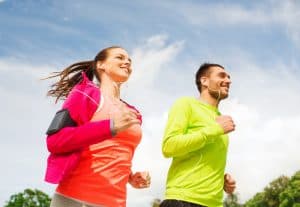 smiling couple with earphones running outdoors