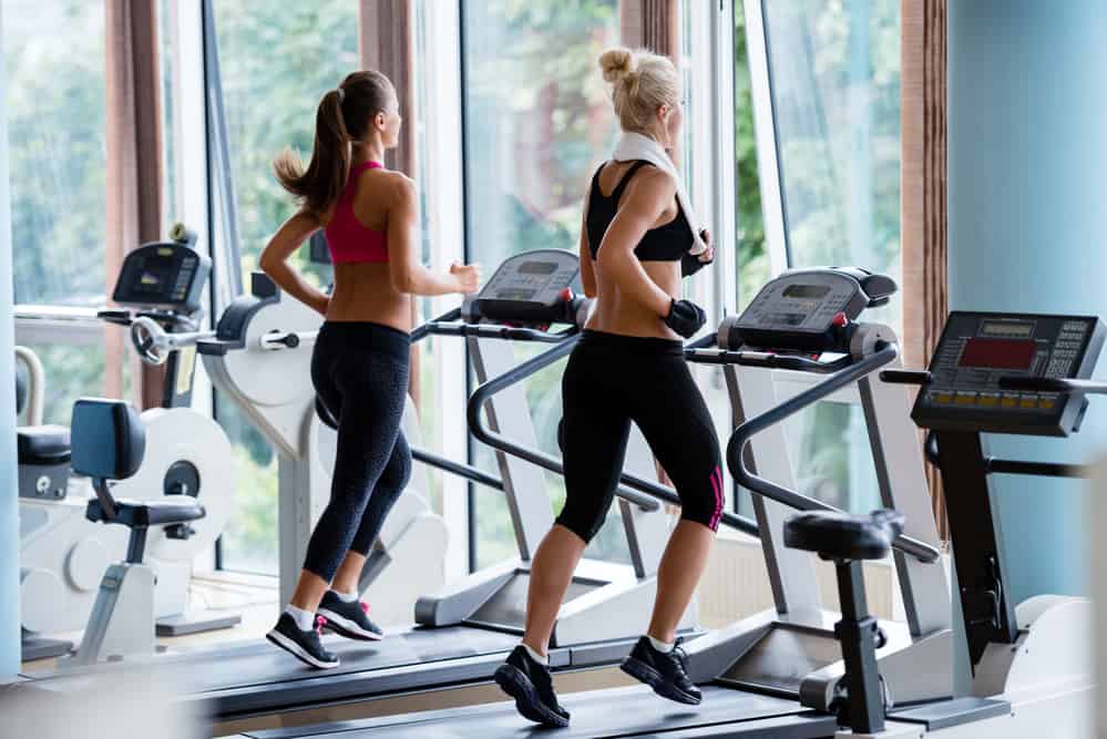 young women exercising on a treadmill at the bright modern gym