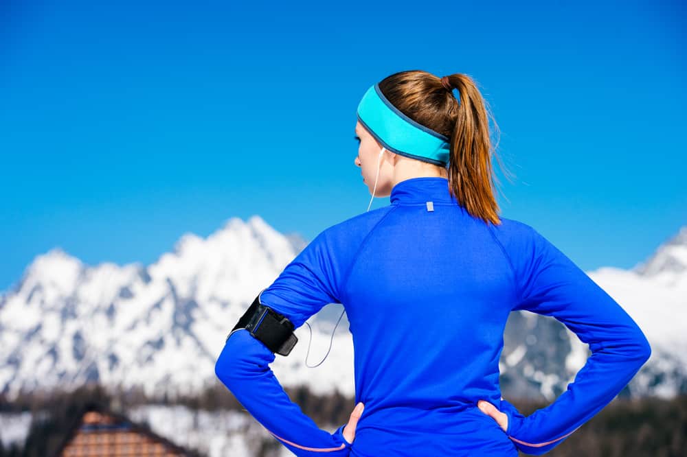 Cold Weather Running Headband:Young woman jogging outside in sunny winter mountains