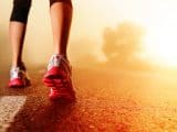 Athlete runner feet running on road closeup on shoe. woman fitness sunrise jog workout welness concept.