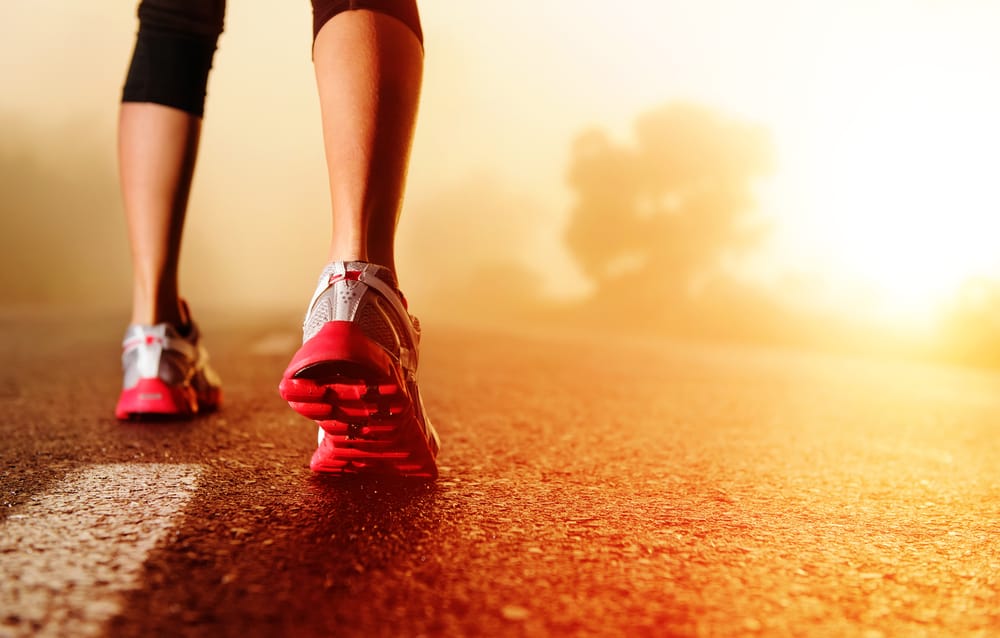 Athlete runner feet running on road closeup on shoe. woman fitness sunrise jog workout welness concept.