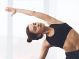 Relaxed girl streching arms and practicing yoga at home