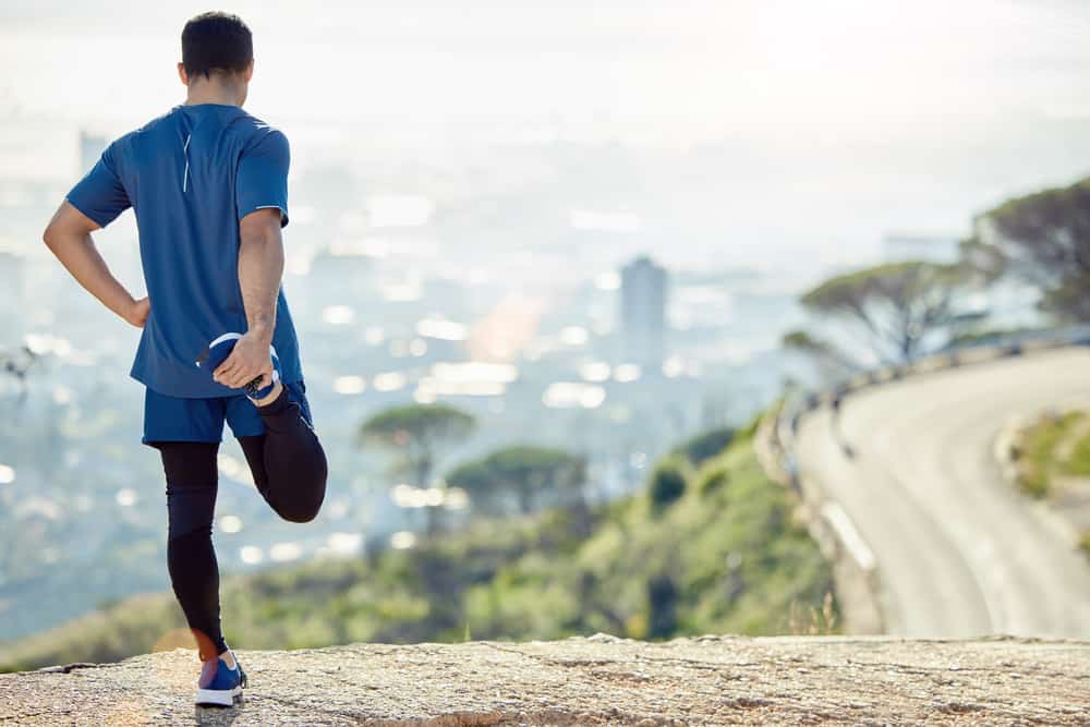 Full length shot of an unrecognisable man standing alone and stretching during his outdoor workout.