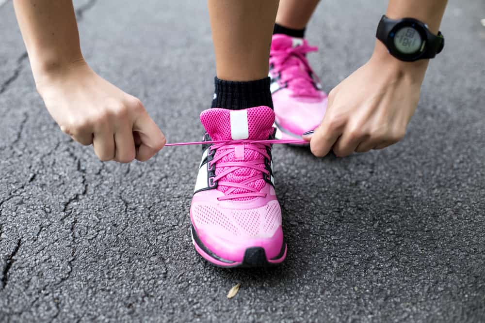 how to keep running when tired:Young woman tying shoelaces