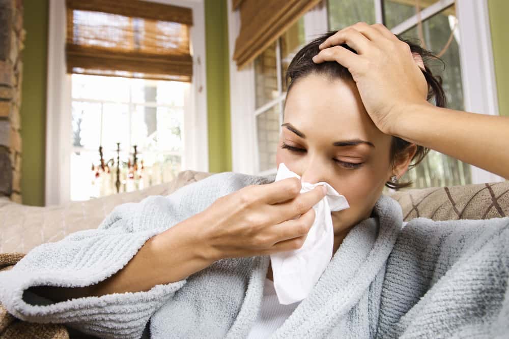 runners flu: Sick young woman blows her nose into a tissue. 