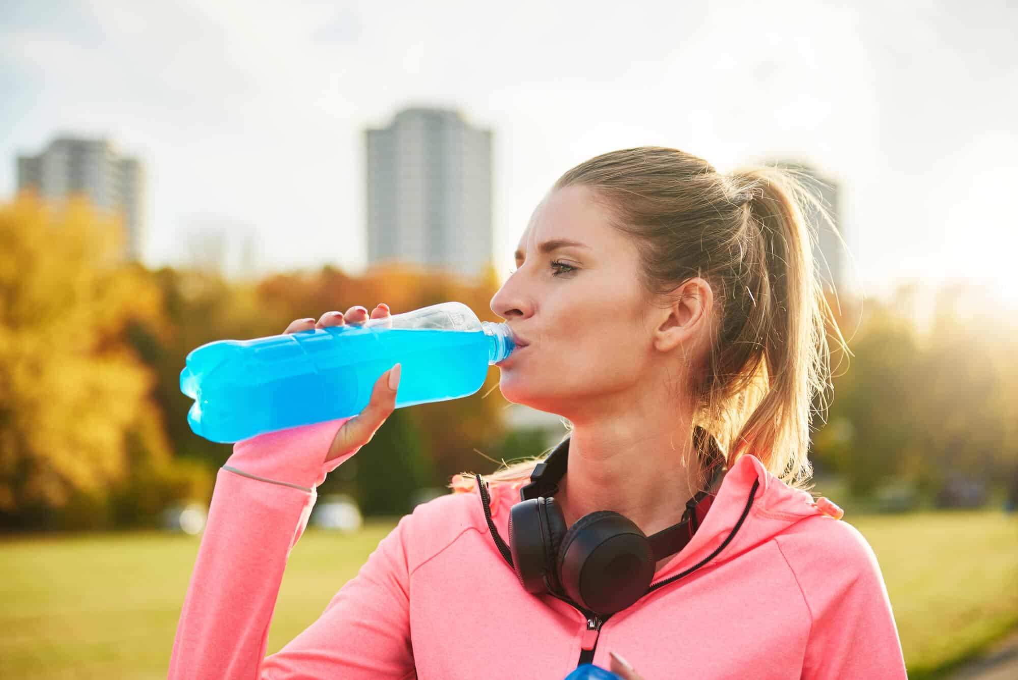 how much water to drink before a marathon:Woman drinking a sports drink